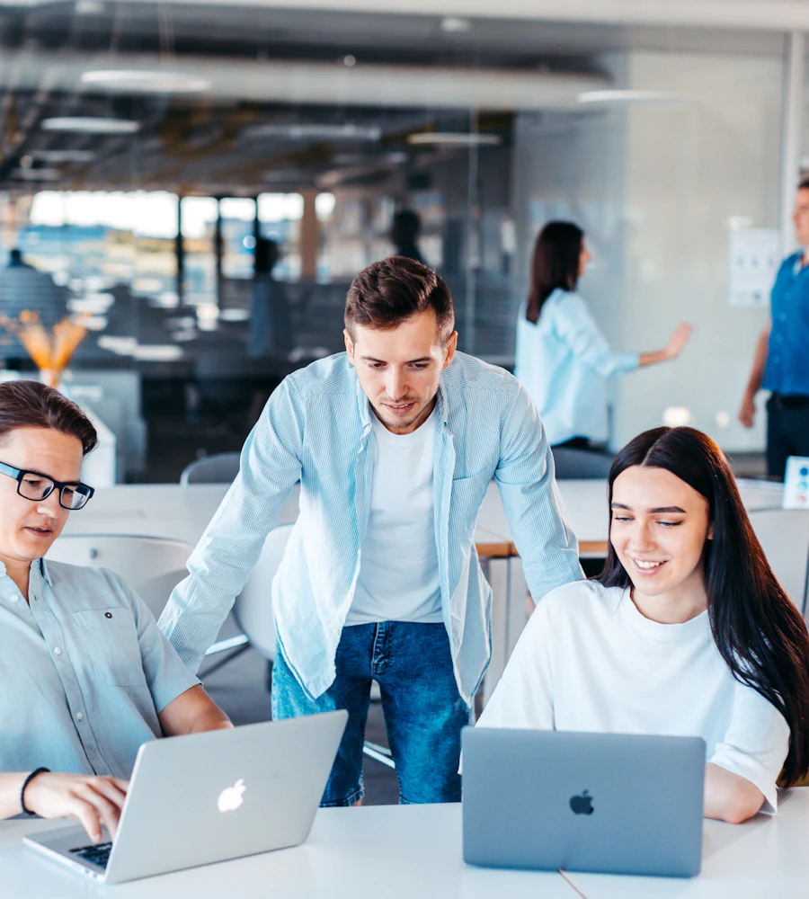 Marketing team working together on laptops in a bright office