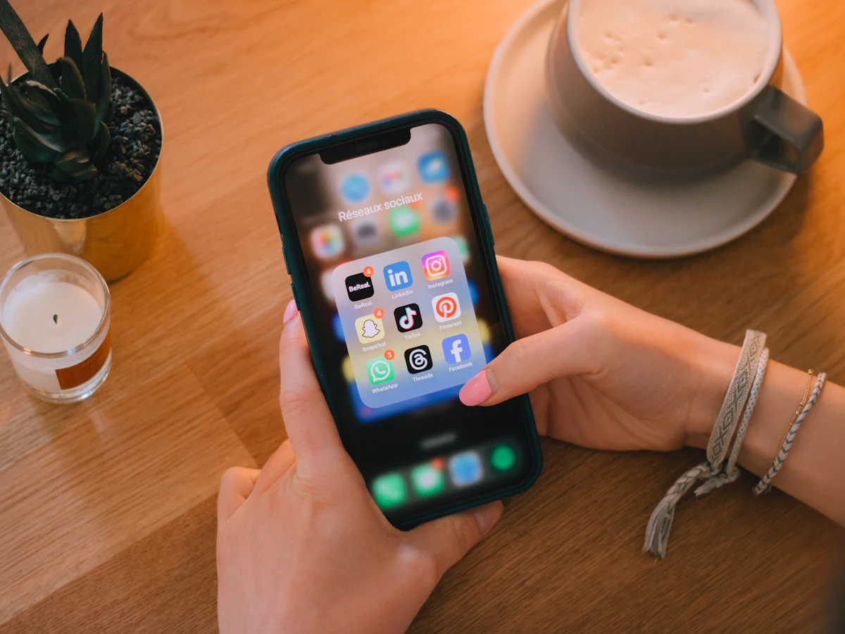 Hands holding a smartphone with social media apps on a café table